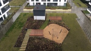 Luchtbeeld van een woongebied met moderne gebouwen, een speeltuin en aangelegde tuinen.