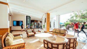 A spacious lobby with a large round coffee table, several sofas, and a television mounted on the wall.