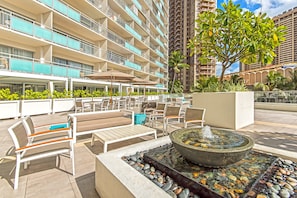 A rooftop lounge with outdoor seating, a fire feature, and a view of a high-rise building. - Ilikai Hotel Renovated Condo Steps Away From Beach w/Free WiFi & Full Kitchen (Honolulu)