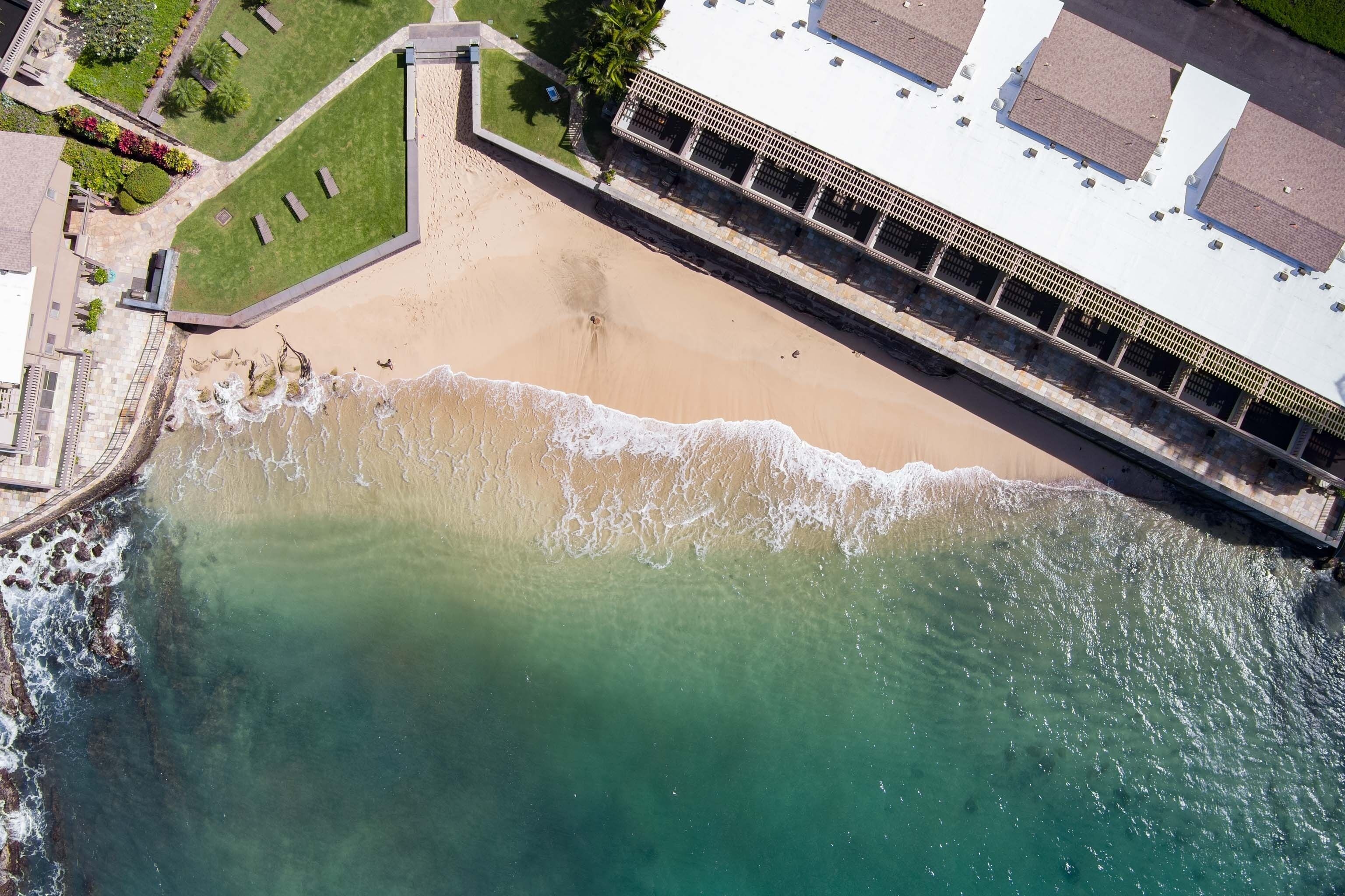 Une vue aérienne d’une plage avec un bâtiment situé à côté.