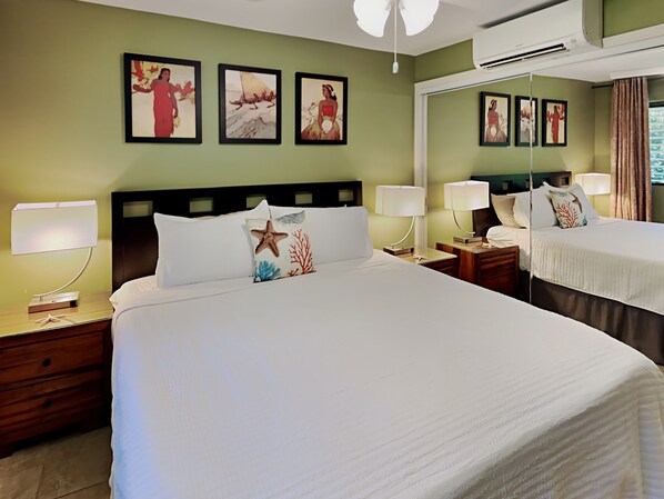 Une chambre d’hôtel avec un grand lit, deux tables de chevet avec des lampes, une petite table de nuit avec une lampe et un climatiseur fixé au mur.