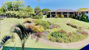 Un jardin aménagé avec une grande variété de plantes et, au fond, un bâtiment équipé de panneaux solaires.