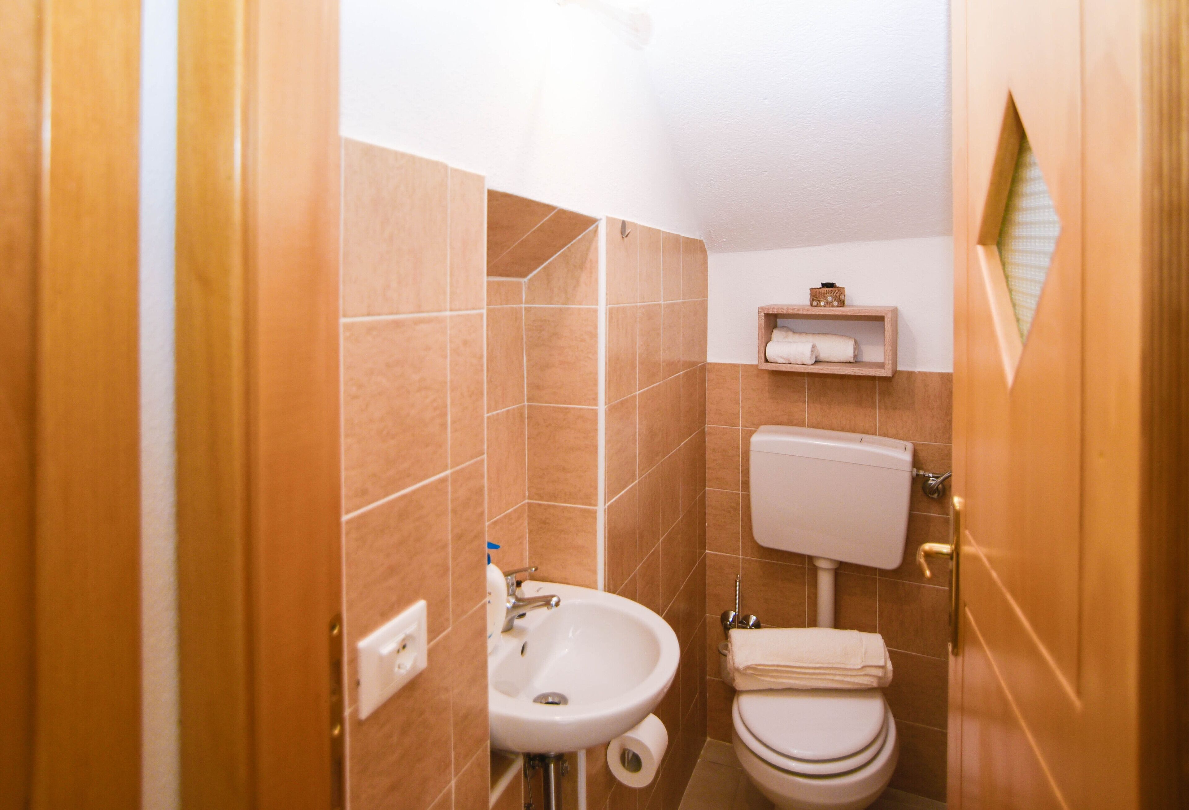 Ein Badezimmer mit Waschbecken, Toilette und einem kleinen Ablagebereich für Toilettenartikel.