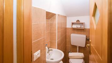 Ein Badezimmer mit Waschbecken, Toilette und einem kleinen Ablagebereich für Toilettenartikel.