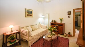 A cozy living room with a sofa, a small table with a lamp, a bookshelf, and a potted plant. - Casa Marta (Nuoro)