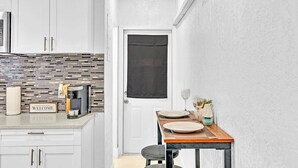 A compact kitchen with white cabinets, a coffee machine, and a welcome sign.