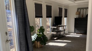 Une pièce spacieuse avec une grande fenêtre, un bureau, une chaise et une plante en pot.