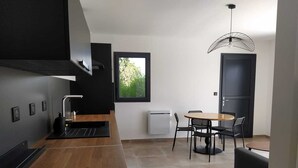 Een moderne keuken met een houten aanrecht, zwarte apparaten en een eethoek met een ronde tafel en stoelen.