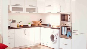 A compact kitchen with white cabinets, a microwave, an oven, and a washing machine. - Immaculate 2-bed Apartment at Pamv Estates Apt2 (Santeo)