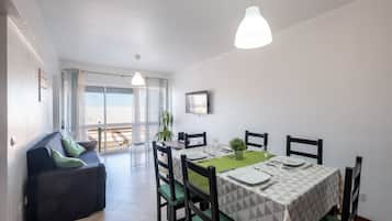A dining area with a table set for four, green cushioned chairs, and pendant lighting.
