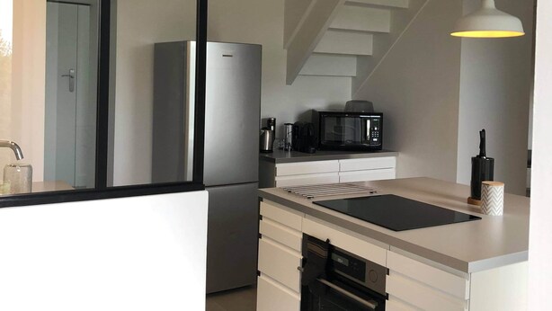 Una cucina moderna con forno integrato, microonde e frigorifero in acciaio inossidabile.