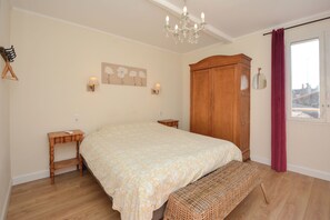 A bedroom with a large bed, a wooden wardrobe, a bench, a small bedside table, and a chandelier. - Townhouse near historical center of Tarascon (Tarascon)