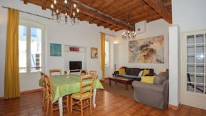 Un área de comedor con una mesa, sillas, un sofá y un cuadro en la pared.