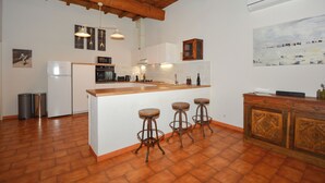 Una cocina con una isla de madera, taburetes de bar, un refrigerador y un armario.