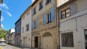 Una hilera de edificios europeos tradicionales con un estilo arquitectónico uniforme, que presenta arcos en las puertas y ventanas con contraventanas.