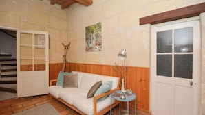 Una sala de estar acogedora con un sofá blanco, una mesita auxiliar, una lámpara y una puerta con un ventanal.