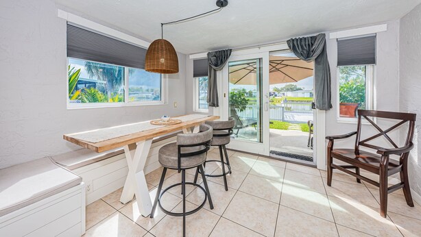 A bright kitchen with a wooden table, bar stools, and a view of the outdoors. - Serene Lakefront home in Tampa Bay, close to beaches and downtown Tarpon Springs (holiday)