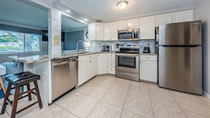 A modern kitchen with white cabinets, stainless steel appliances, and a large island with a built-in dishwasher. - Serene Lakefront home in Tampa Bay, close to beaches and downtown Tarpon Springs (holiday)