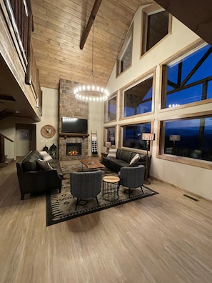 Un salón amplio con chimenea, ventanas grandes y un techo alto.