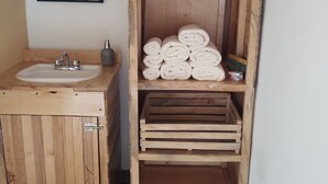A wooden bathroom with a sink, mirror, and shelves holding rolled towels. - Cabañas Santa Brígida Huasca (Huasca de Ocampo)