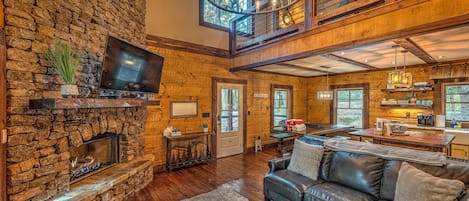 A spacious living area with a stone fireplace, leather sofa, and a large flat-screen TV.