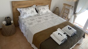 Un letto ben rifatto con biancheria da letto floreale, una testiera in legno e una coperta marrone.
