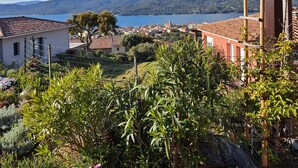 Un quartiere residenziale con case, un giardino e vista su un lago e montagne.