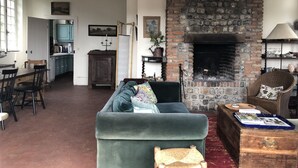 Een gezellige woonkamer met een open haard, een eethoek en een keuken op de achtergrond.