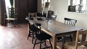 Een eetgedeelte met een houten tafel en stoelen, een raam met uitzicht en een deur.