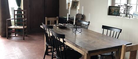Un comedor con una mesa y sillas de madera, una ventana con vistas y una puerta.