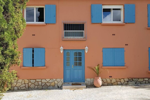 A building with a stone foundation, a blue door, and multiple windows with blue shutters. - Beau T3 -terrasse & Parking, Proche Plage 1er Étage Droite (Hyères)