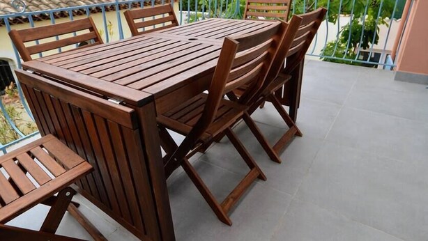 A wooden table and chairs on a balcony with a view of trees and buildings. - Beau T3 -terrasse & Parking, Proche Plage 1er Étage Droite (Hyères)