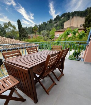 A wooden table and chairs on a balcony with a view of trees and buildings. - Beau T3 -terrasse & Parking, Proche Plage 1er Étage Droite (Hyères)
