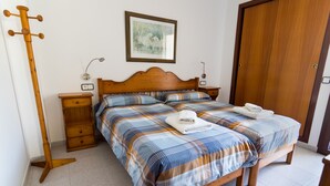 A bedroom with a wooden bed, two bedside tables, a nightstand, a wooden floor, and a door. - Apartamento Coral, Holiday Apartment in Puerto Pollença (Puerto Pollença)