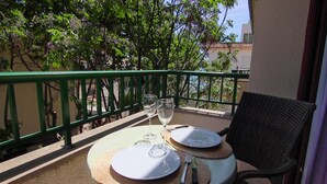 A small outdoor table with two plates, two wine glasses, and cutlery on a balcony with a green railing. - Apartamento Coral, Holiday Apartment in Puerto Pollença (Puerto Pollença)
