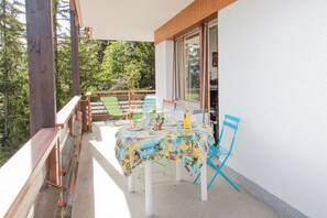 Un balcón con mesa lista para dos personas, rodeado de barandillas de madera y sillas.