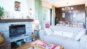 En hyggelig stue med pejs, sofa, fjernsyn og spisebord.