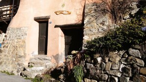 Un edificio rústico con base de piedra, estructura superior de madera y un pequeño balcón con barandilla de madera.