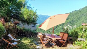 Un patio con una mesa y sillas, cerca de madera y un muro de piedra.