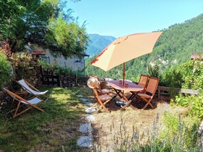 Eine Terrasse mit Tisch und Stühlen, einem Holzzaun und einer Steinmauer.