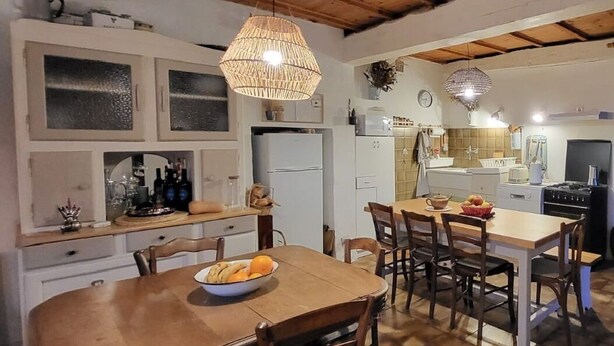 Una cocina rústica con vigas de madera, una mesa de comedor con sillas y una lámpara colgante.