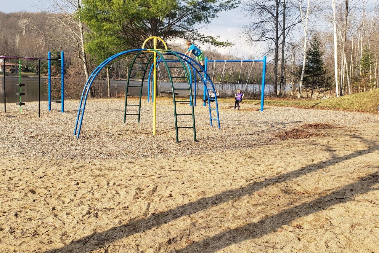Un parque infantil con estructuras para escalar y suelo de arena.