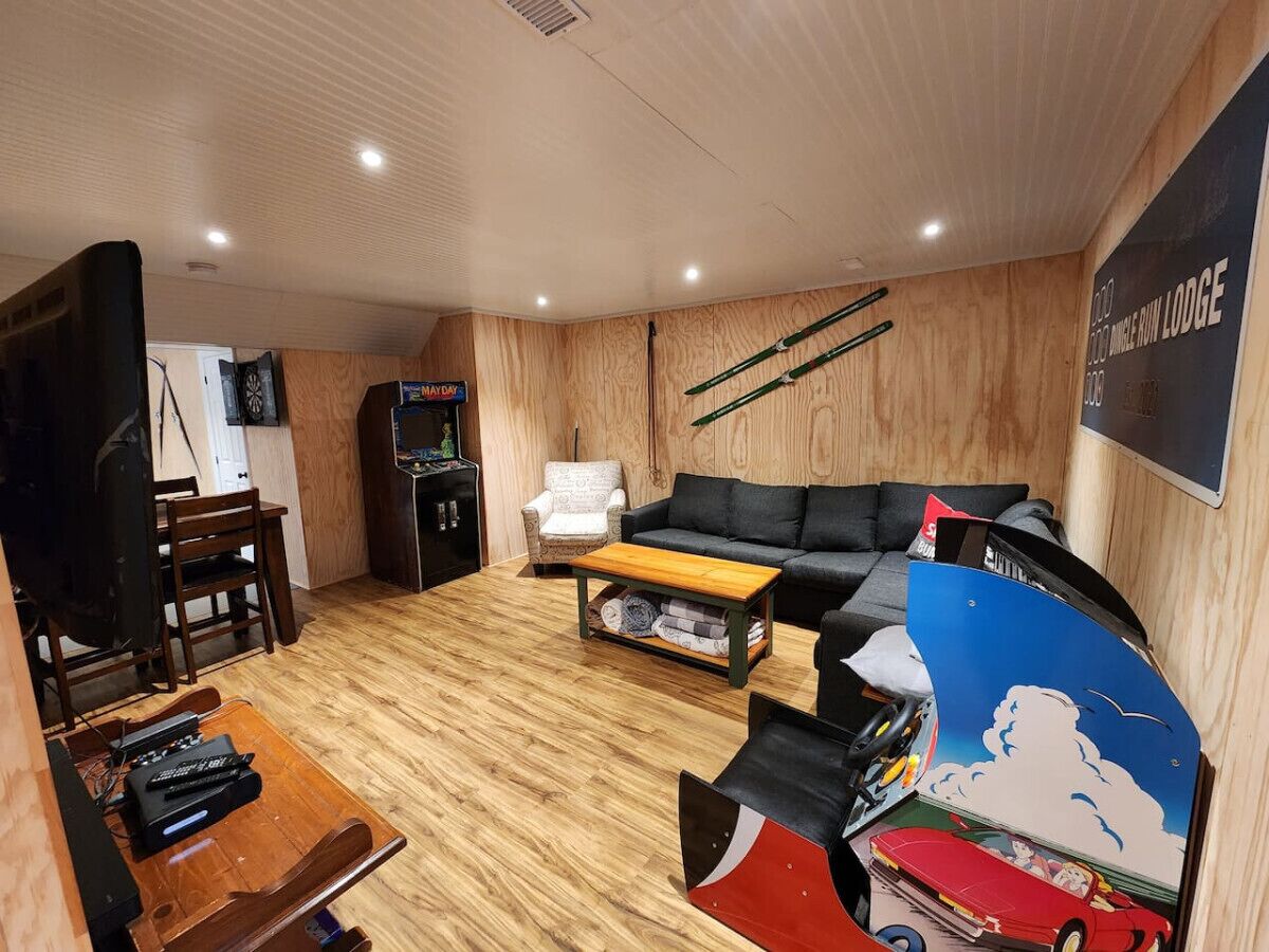 Ett mysigt vardagsrum med en soffa, ett soffbord och en tv. Det finns ett trägolv och en skylt med texten "MAYDAY".