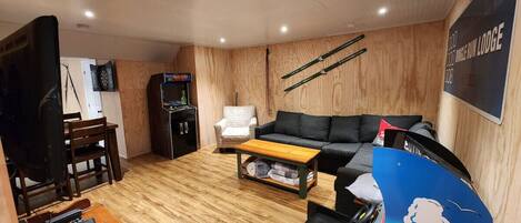 A cozy living room with a sofa, coffee table, and a TV. There's a wooden floor and a sign that says "MAYDAY".