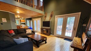 A spacious living room with a dark-colored sofa, a wooden coffee table, and a television on a stand. - "Dingle Run Lodge" at Sir Sam's (hot tub/sauna) (EAGLE)