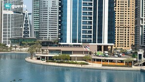 Een modern hotel met uitzicht op het water, met hoge gebouwen op de achtergrond.