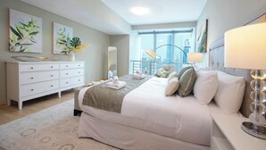 Een moderne hotelkamer met een groot bed, een witte dressoir, een spiegel en uitzicht op de stad.