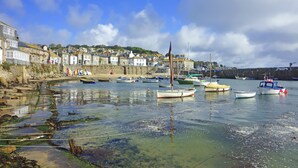 A coastal town with boats docked at the harbor, stone buildings, and a clear sky. - Peaceful countryside retreat with sea views (Penzance)