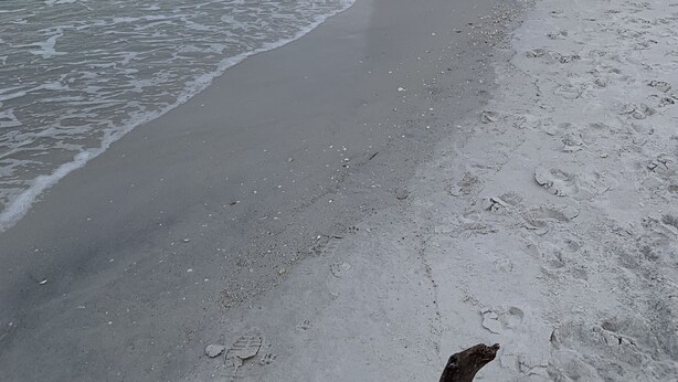 Een strand met een zandstrand en rustige golven.