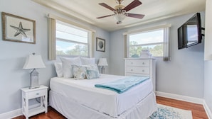 A bedroom with a bed, two bedside tables, a ceiling fan, a TV, and two windows. - Spacious two-bedroom apartment with private, heated pool (near beaches) (St. Petersburg)
